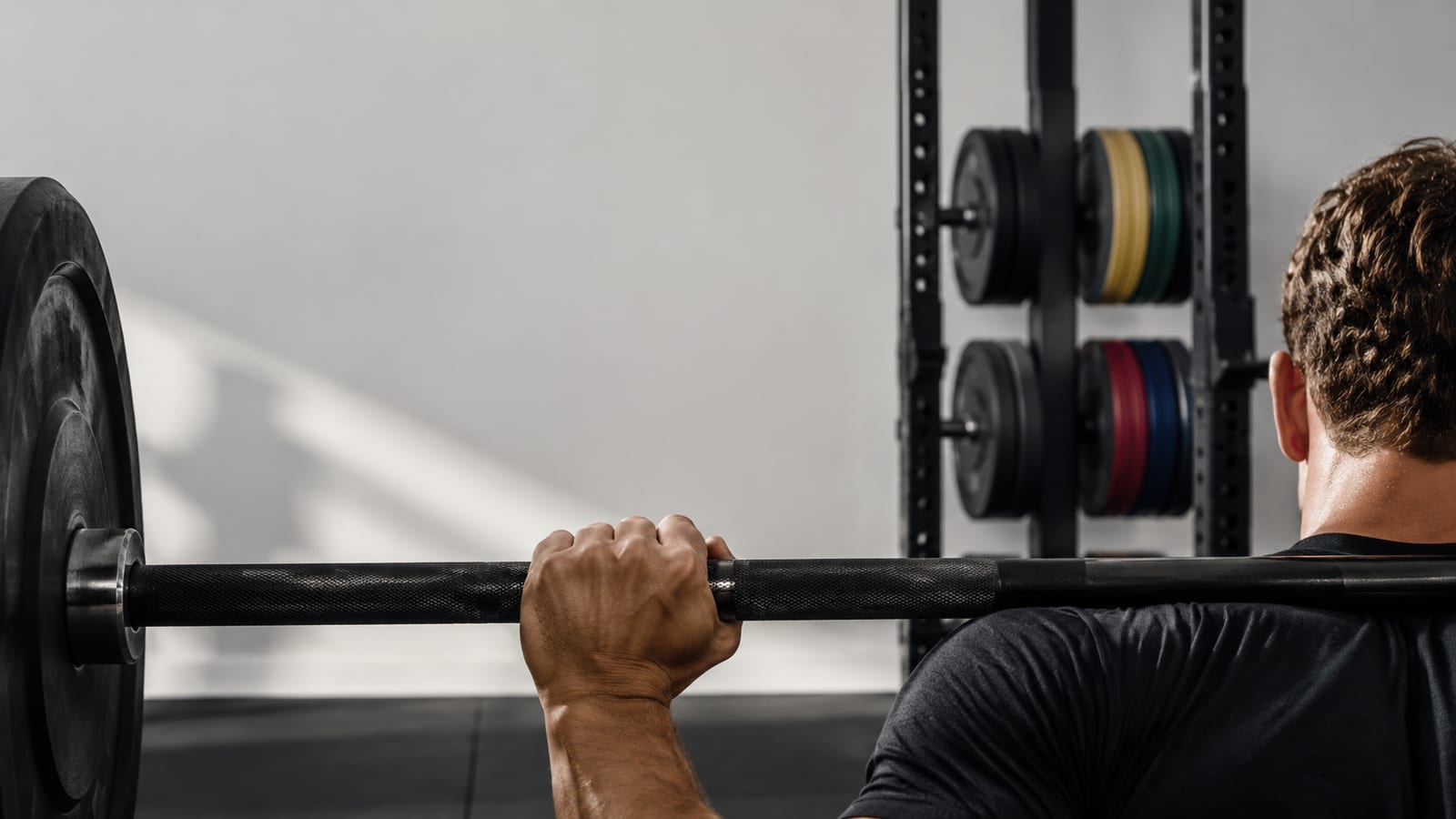 Barbell lifter preparing for repeated working sets beside loaded plates