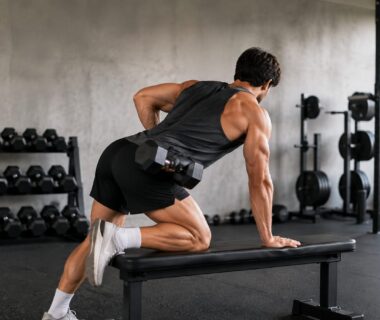 Athlete performing controlled single-arm dumbbell row while comparing balanced shoulder positions in a gym