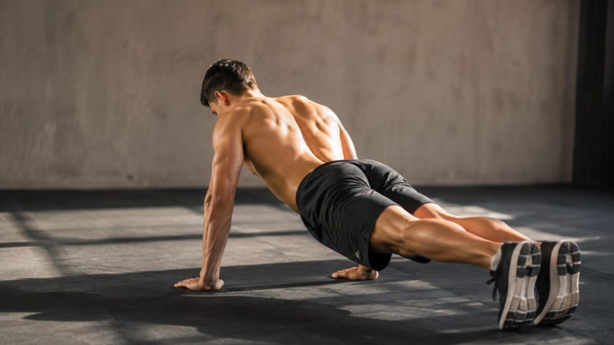 Athlete performing a controlled scapular push-up in a bright strength-training gym