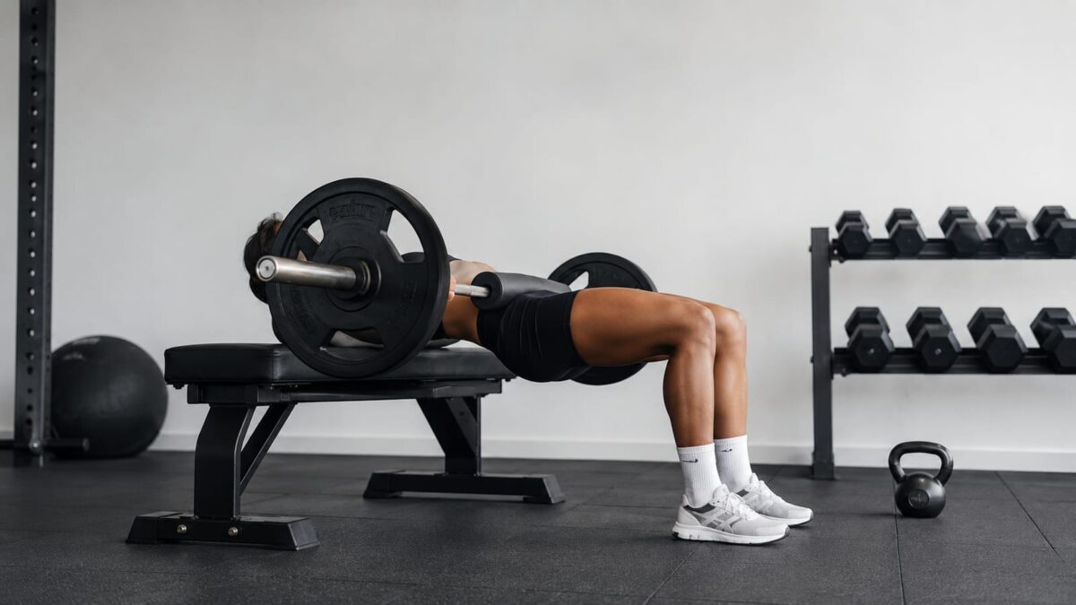 Athlete finishing barbell hip thrust to build strong sculpted glutes