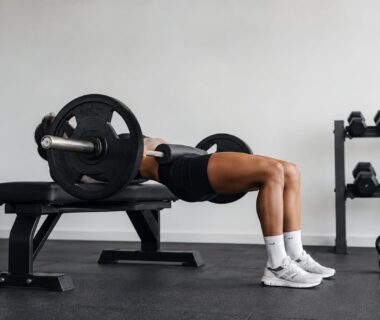 Athlete finishing barbell hip thrust to build strong sculpted glutes