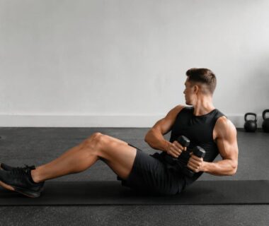 Athlete performing a controlled weighted Russian twist on a gym mat with knees bent