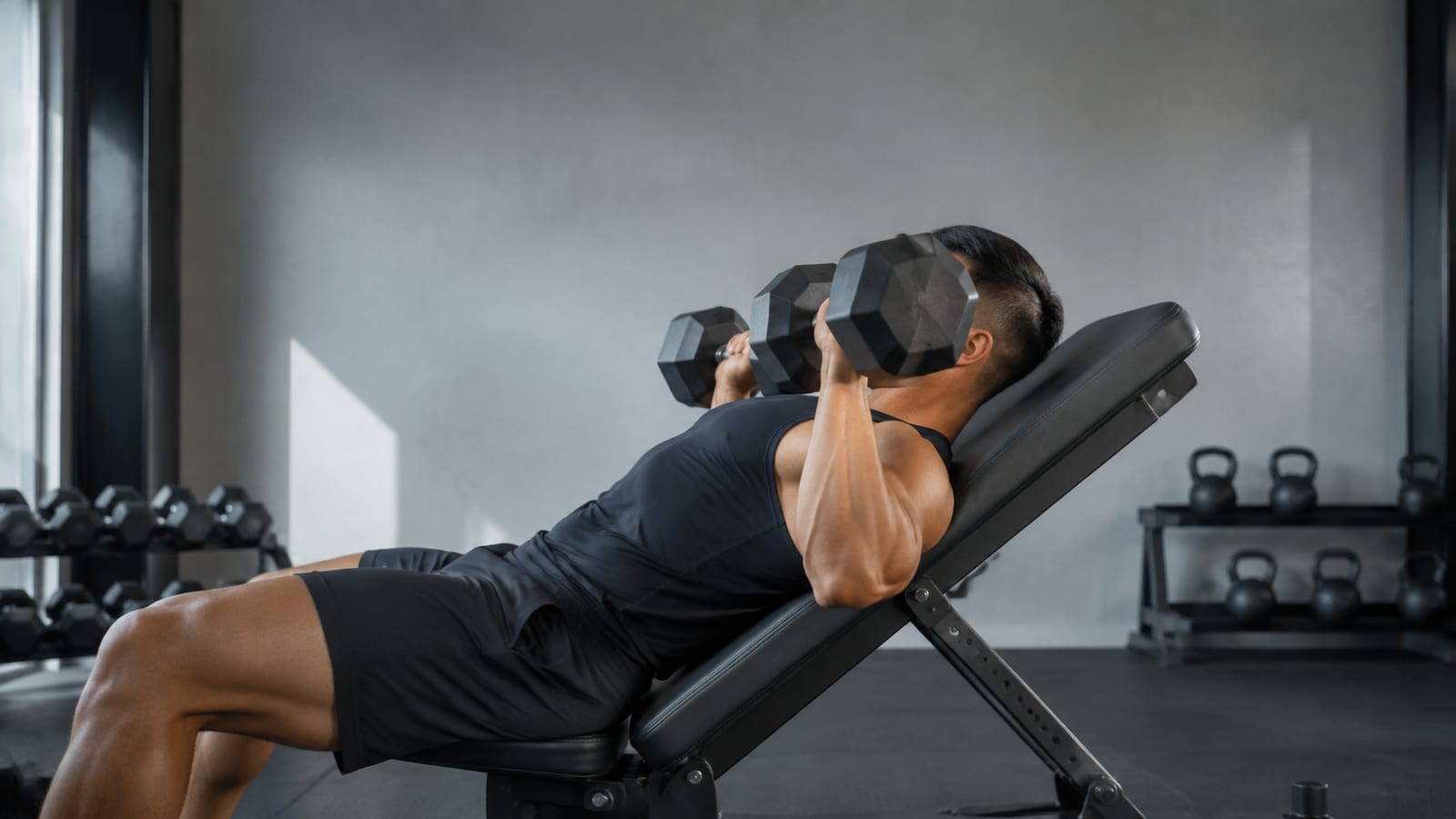 Lifter performing controlled dumbbell presses after a brief rest between demanding mini-sets