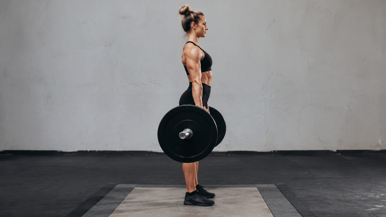 Lifter locked out at top of conventional barbell deadlift with solid form