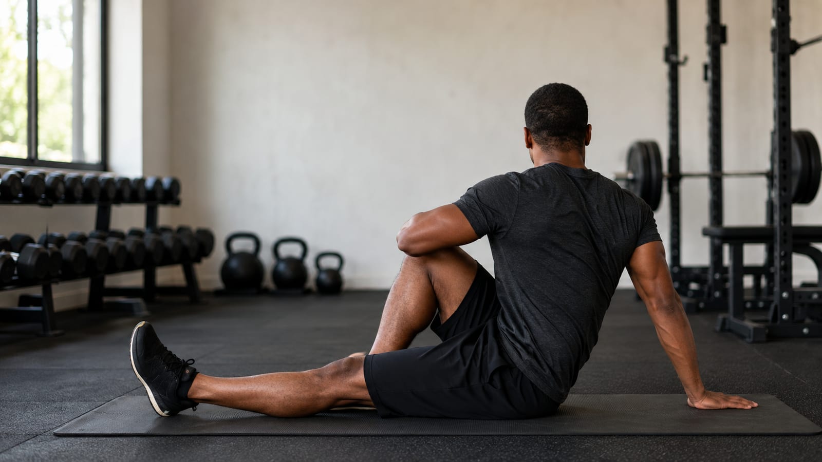 Strength athlete stretching hips and shoulders on a gym mat after full-body training