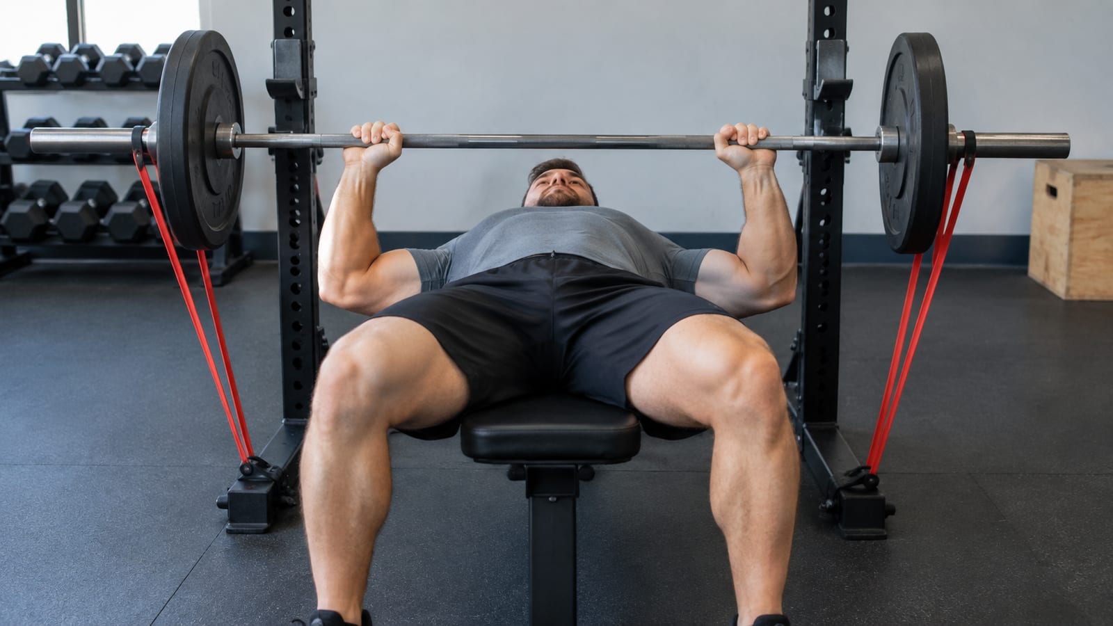 Band-resisted bench press photographed from the foot end of the bench in a gym